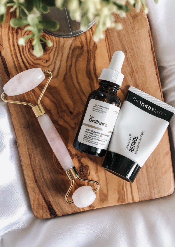 rose quartz facial roller next to rose hip oil and retinol serum